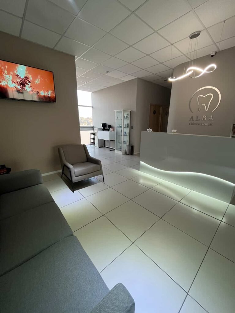 Área de recepción de Alba Clínica Dental con diseño moderno, iluminación elegante y sala de espera cómoda.